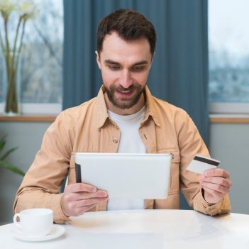 front-view-man-shopping-online-using-tablet-credit-card_23-2148455096